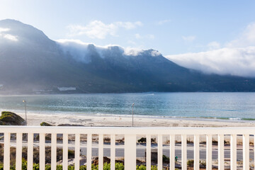Scenic ocean view from balcony overlooking serene beach and majestic mountains, copy space