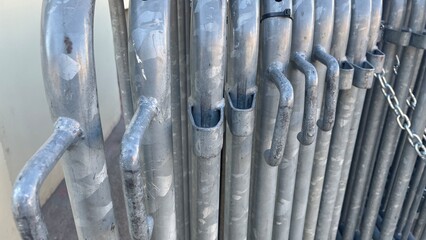 Metal barricades lined up against a wall in the bright sunlight on a warm afternoon in an urban setting