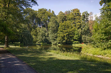 Stone walkway in the park. Park on a sunny summer day. Park with a stone walkway. Trees and grass illuminated by the sun's rays. Park without people.