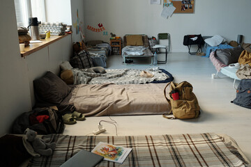 Row of sleepers of refugees or homeless people with plaids, cushions, backpacks and bags with...