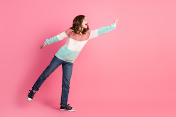 Young pretty girl wearing a colorful sweater posing cheerfully against a pink background