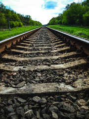 The railway tracks go on forever, creating an effect. The contrast between green nature and industrial road lines.