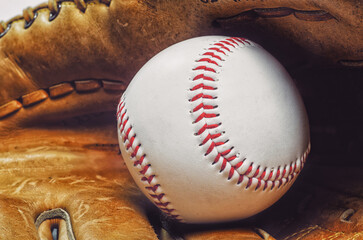 Baseball in leather glove with red stitching on white background