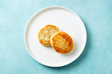 Chicken patties, cutlets on a white plate. Blue background. Top view.