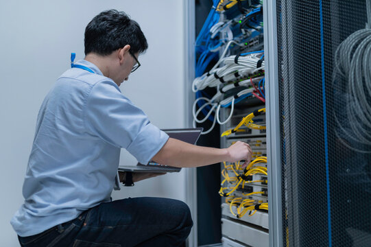 Computer engineer is setting up network in server room,Systems Maintenance Technician,Male engineer working in server room at modern data center