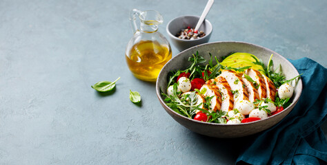 Warm chicken salad with avocado and mozzarella cheese. Grey background. Copy space.