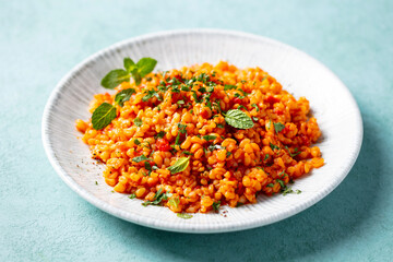 Bulgur with tomatoes on a white plate. Blue background. Close up.