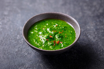 Chimichurri, green parsley and chili sauce in a bowl. Dark background. Close up.