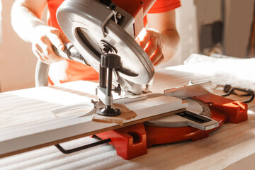 Circular saw in action as a carpenter skillfully cuts wooden planks. Hands hold the wood against the saw, showcasing precision and craftsmanship in woodworking
