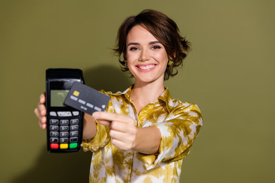 Confident young businesswoman showcasing payment with a credit card reader in front of khaki background