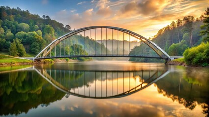Serene sunrise illuminates modern arch bridge reflecting in tranquil waters, surrounded by lush green hills