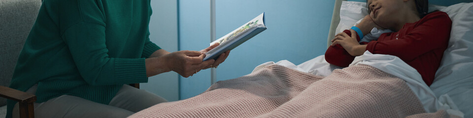 Header with grandmother reading book to her granddaughter in the ward