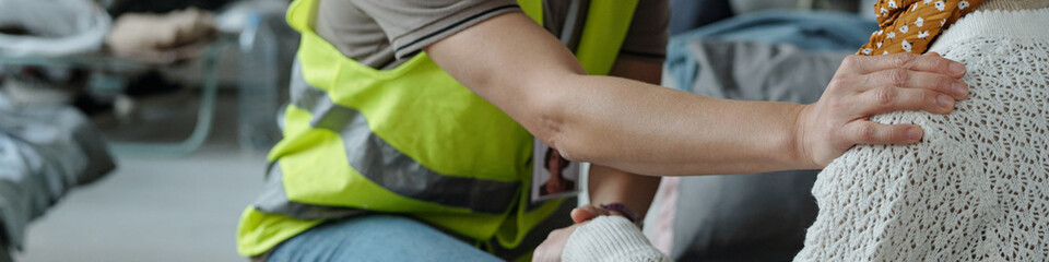 Header of hand of mature female volunteer on shoulder of senior migrant or refugee during...