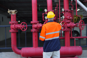 Male engineer inspects water pipelines in the engineering system area of the factory outside where...