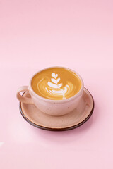 Cappuccino in a beige cup isolated on the pink background