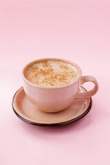 Coffee latte in a beige cup isolated on the pink background