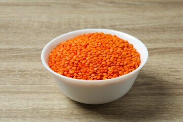 Red lentils in a bowl on a wooden background