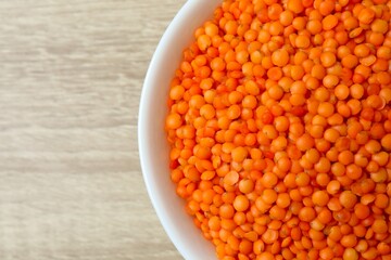 Red lentils in a bowl on a wooden background