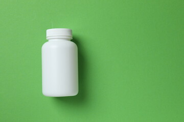 White bottle on green background, top view