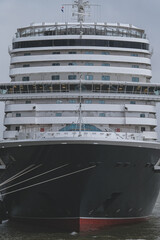 Naklejka premium Brand new ocean liner cruiseship cruise ship Queen Anne in port of Rotterdam, Holland with skyscraper downtown city skyline