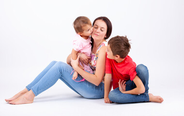 A woman is holding two children, one of whom is kissing the other