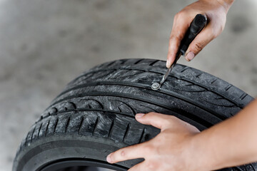 Mechanic is removing a nail from a tire so he can patch it so it can be used again.