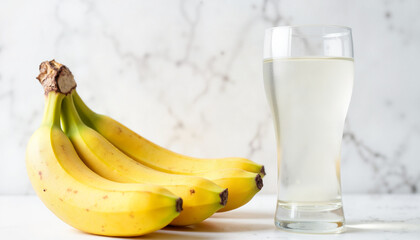 Fresh bananas and a glass of lemonade on a marble background