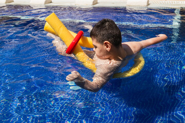 Child with cerebral palsy swimming in pool with floatation devices