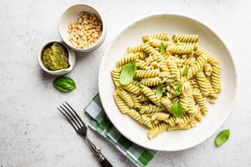 Italian Fussili pasta with basil pesto and fresh basil on white stone background. Top view.