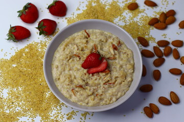 Healthy proso millet porridge topped with fresh sliced strawberries in a bowl