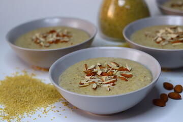 Porridge made of proso millet served in a bowl, topped with chopped badam