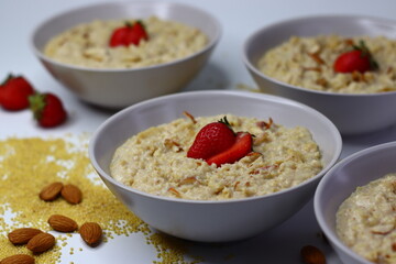 Healthy proso millet porridge topped with fresh sliced strawberries in a bowl