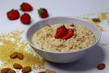 Healthy proso millet porridge topped with fresh sliced strawberries in a bowl