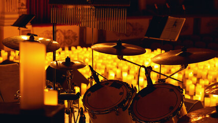 A close-up of a drum set with cymbals and chimes in the foreground, surrounded by numerous lit...
