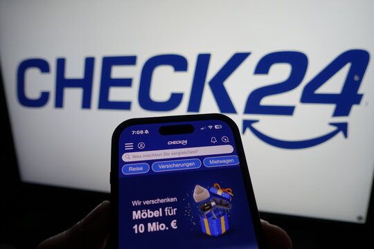 Kiel, SH, Germany March 20 2025: Smartphone displaying Check24 website in front of company logo on a monitor, illustrating digital service offerings