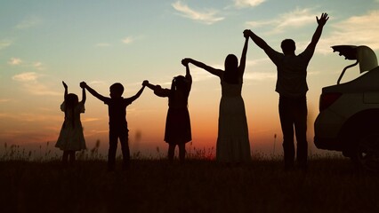 Big family at sunset holding hands, silhouettes. Happy people children parents lined up according to height held hands raised in air with joyful cheerful feeling of freedom anticipation of journey.