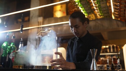 Asian bartender serving mist smoky classical mixing whiskey cocktail fantastic presentation, recommending special welcome tasty creative advertisement drink at beverage counter bar luxury. Vinosity.