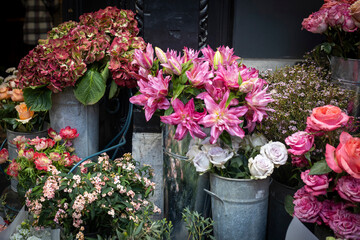 Burgundy lilies beside a bouquet of hydrangeas, red anemones, buttercups, orange roses, and eucalyptus branches for special occasions like weddings, dates, and funerals.