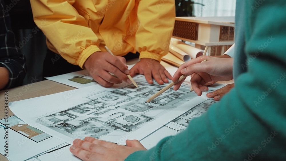 Poster hands actively engage with detailed architectural blueprints and sketches, showcasing collaboration 