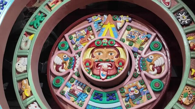 A colorful calendar with a man's face on it. The calendar is made of clay and has a blue background