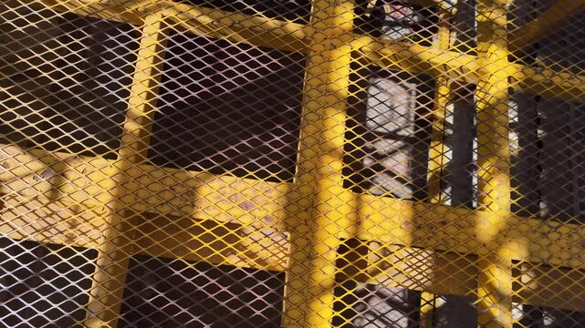 A yellow metal fence with a mesh pattern. The fence is on a building