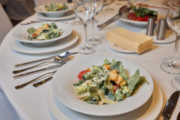 An elegant dinner setting with Caesar salad and fine dining essentials for a culinary experience
