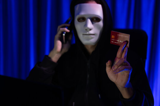 White criminal anonymous mask calling to credit card owner to threaten ransom with privacy information all database, making password encryption by programming hack trying to make insecure. Pecuniary.