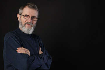 Portrait of mature man with crossed arms on black background, space for text