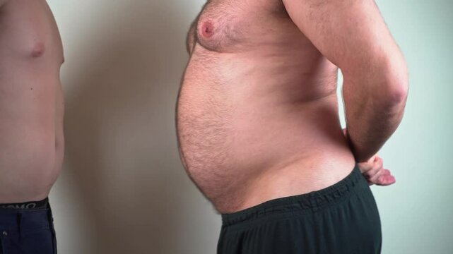 Two man funny belly shake. Crazy stomach dance. Overweight man joking. Calorie fight challenge. Hilarious waistline struggle. Silly belly jiggle. Playful stomach pat. Healthy figure humor.