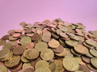 An Abundant Pile of Various Coins Displayed on a Colorful Pink Background Surface