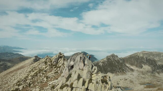 A mountain climber advancing among sharp rocks above the clouds... Nature, freedom and the spirit of pushing the boundaries come to life in this frame. The summit is one step away.