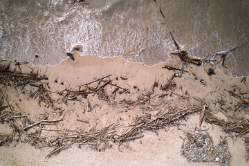 An top view of a polluted beach. Ocean waves bring garbage to the shore.The problem of ecology and pollution of nature and the planet.