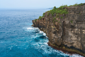 Cinematic aerial landscape shots of the beautiful island of Nusa Penida. Huge cliffs by the shoreline and hidden dream beaches with clear water and foaming wave.