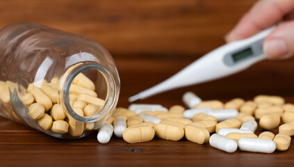 Antibiotic and aspirin pills with a digital thermometer, fever meter. Flu concept.